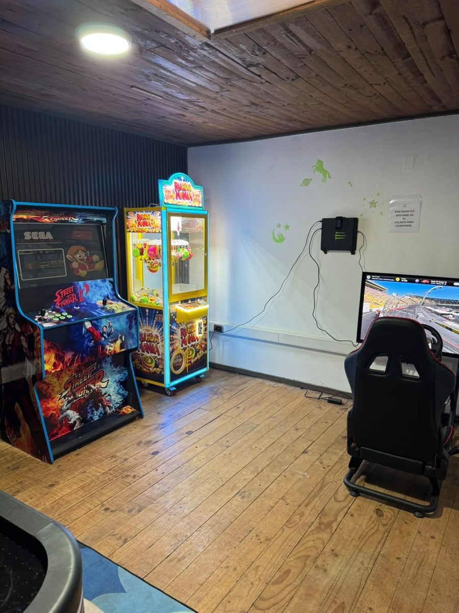 Zona arcade con máquinas de videojuegos y simulador de conducción