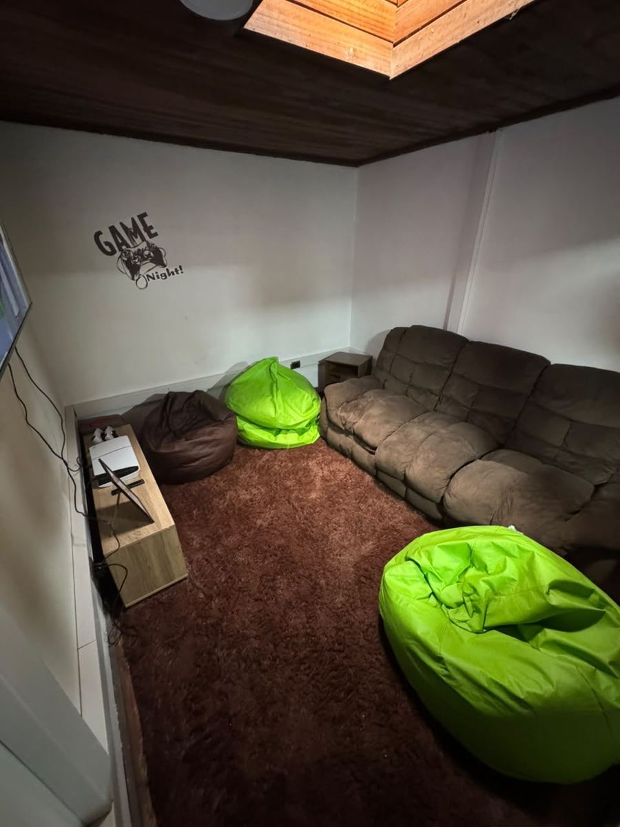 Sala gamer con sillón y pufs frente al televisor